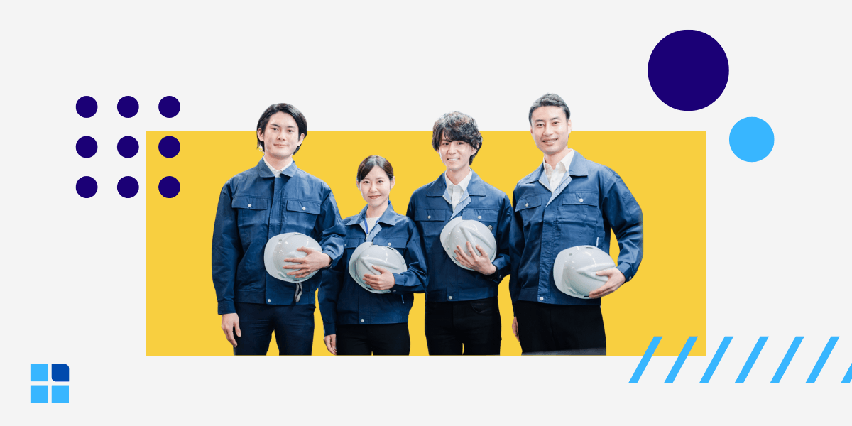 A team of four smiling industrial workers in matching blue jackets, holding their white hard hats.