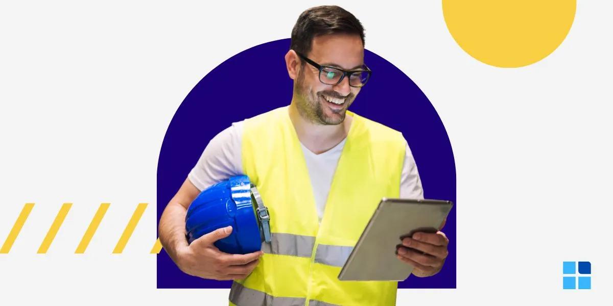 Smiling man in a yellow safety vest holds a blue hard hat and tablet.