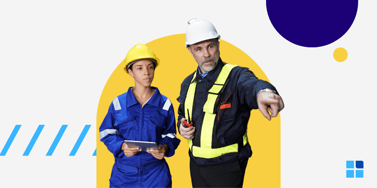 Two construction workers in hard hats and safety gear discuss a project.