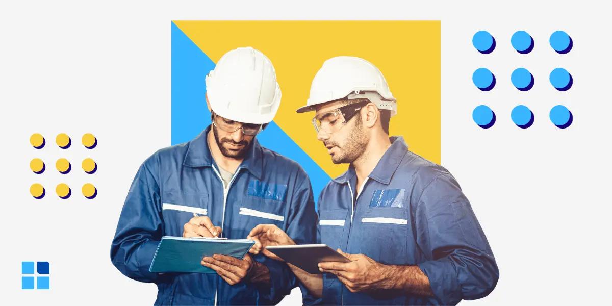 2 construction workers in blue uniforms & white helmets review documents on a clipboard and tablet.