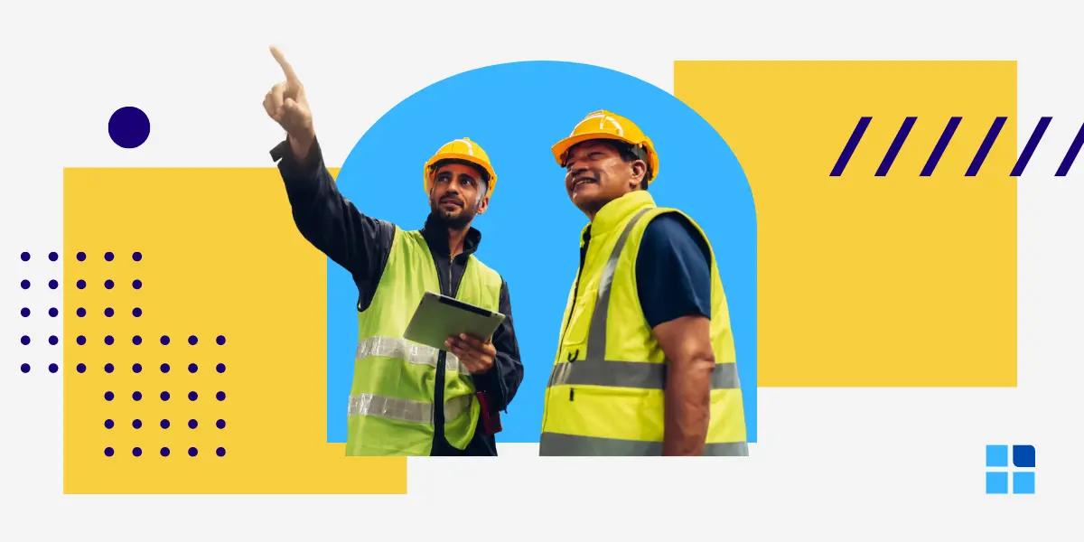 Two construction workers in yellow safety vests and helmets discuss a project.