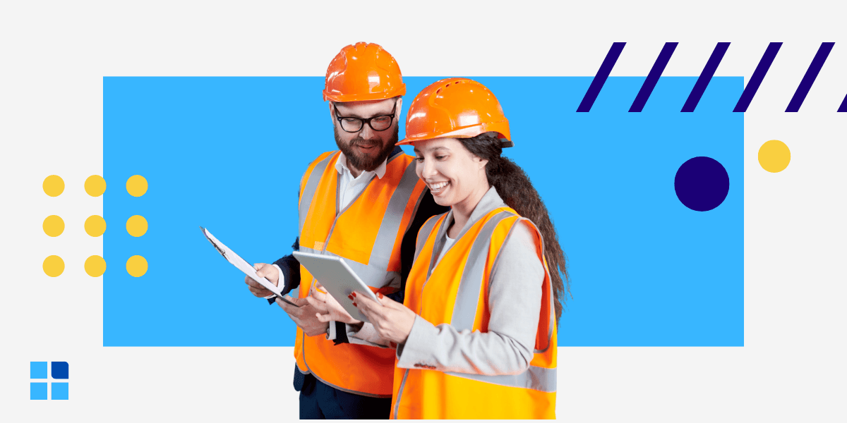 Two construction workers in orange vests and helmets smile while reviewing plans on a tablet.