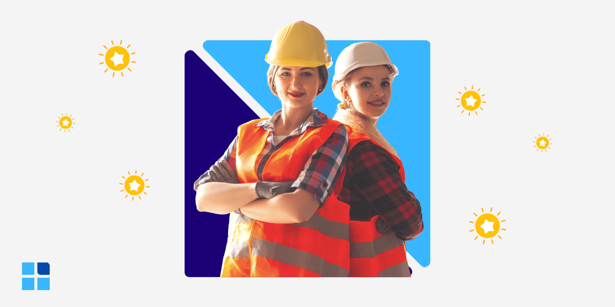 Two women in construction hats and orange vests stand confidently.