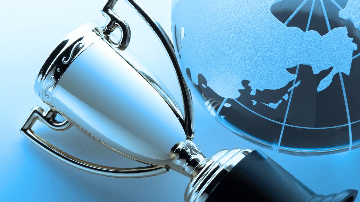 A gleaming silver trophy next to a frosted globe, symbolizing excellence and global reach in world-class manufacturing.